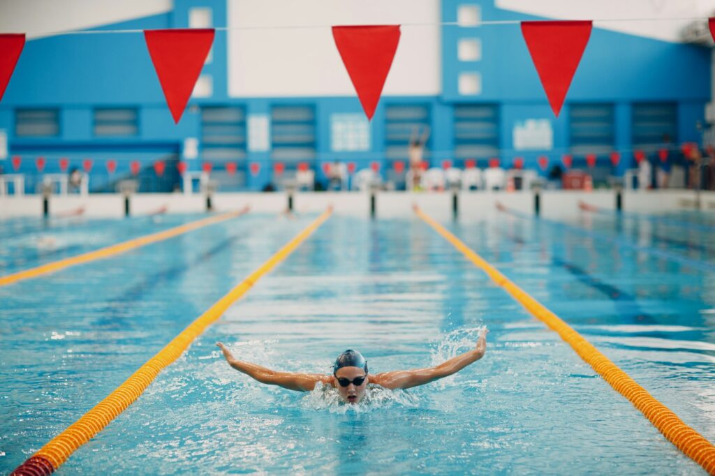 Young woman swimmer swims in swimming pool.